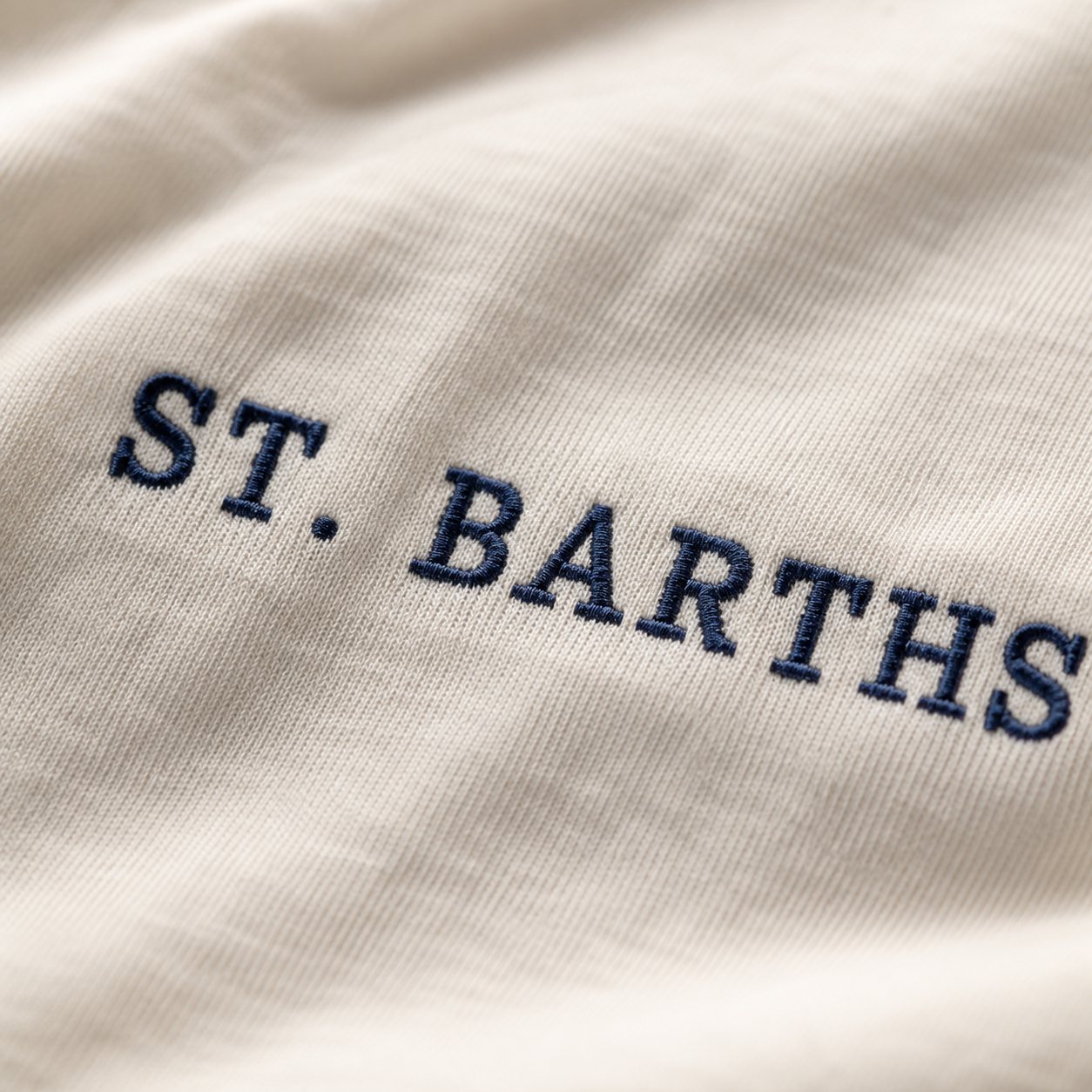 Macro close-up of ST. BARTHS chest embroidery in dark navy thread